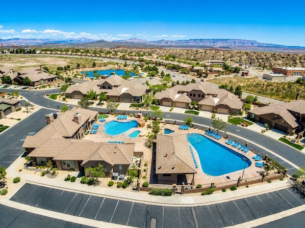 A residential area with multiple houses, a large swimming pool, and a clear view of mountains in the background.