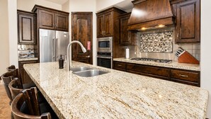 Una cocina con encimeras de granito, electrodomésticos de acero inoxidable y armarios de madera oscura.