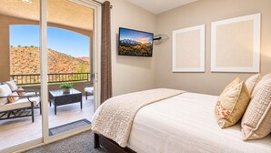 Un dormitorio con una cama grande, un balcón con vistas a un paisaje desértico y un cuadro en la pared.