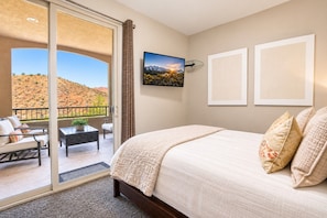 Una camera da letto con un letto grande, un balcone vista su un paesaggio desertico e un quadro appeso al muro.