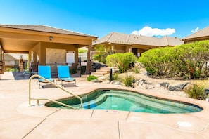Una piscina con una scaletta in metallo, circondata da sdraio e un'area patio coperta.