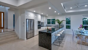 A modern kitchen with a central island, stainless steel appliances, and a dining area with bar stools.