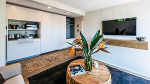 Una cocina moderna con armarios blancos, una isla de madera y una zona de comedor con una mesa redonda.