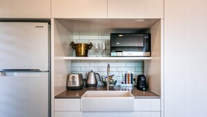 Cocina compacta con refrigerador Samsung, microondas, hervidor, tostadora y pileta.