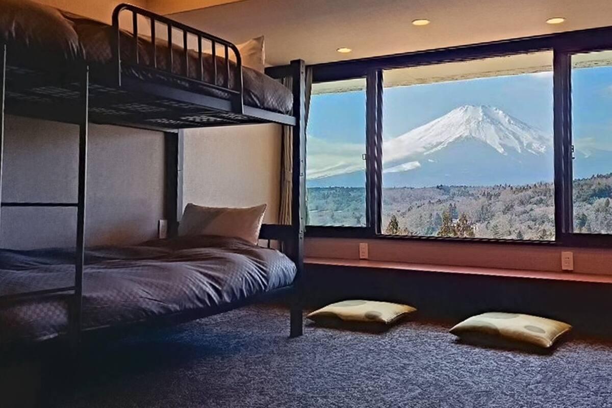 A bunk bed room with a large window offering a mountain view.