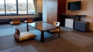 A modern conference room with a large table, four chairs, a small kitchenette, and a TV mounted on the wall. - Rokumeikan HILLS (Yamanakako)