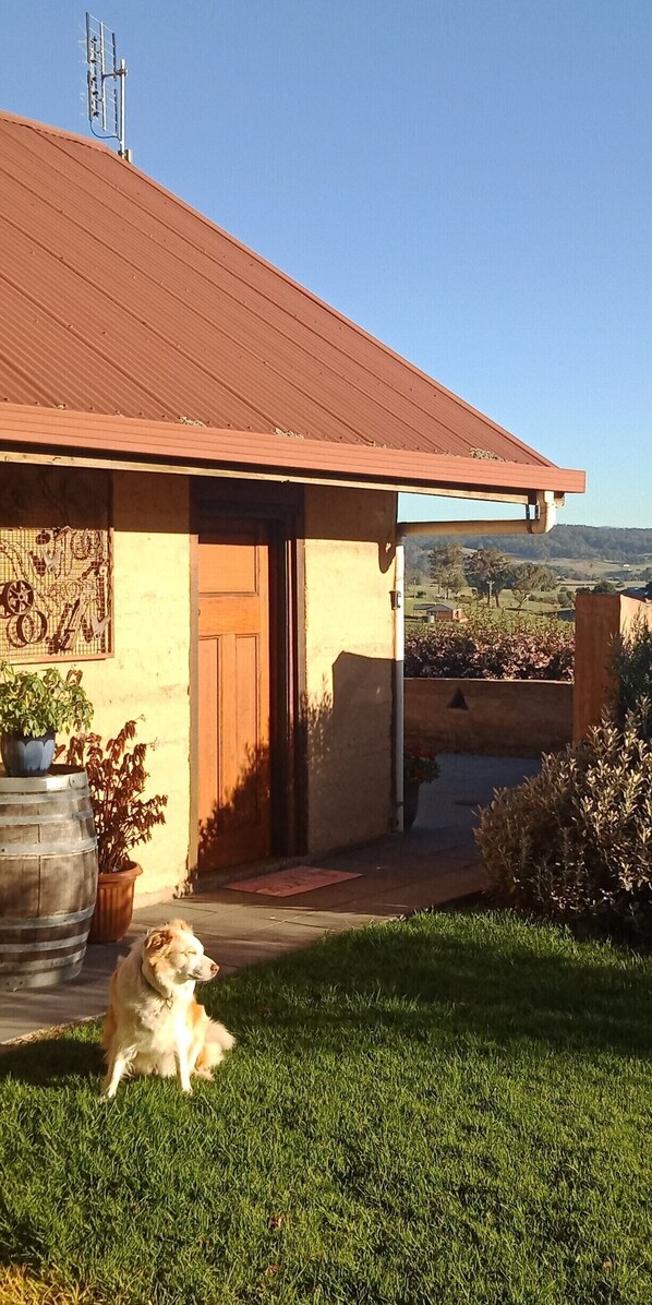 A house with a red roof, a wooden door, and a small porch. - Gingko Lodge. Country luxury with a view. (Mossiface)