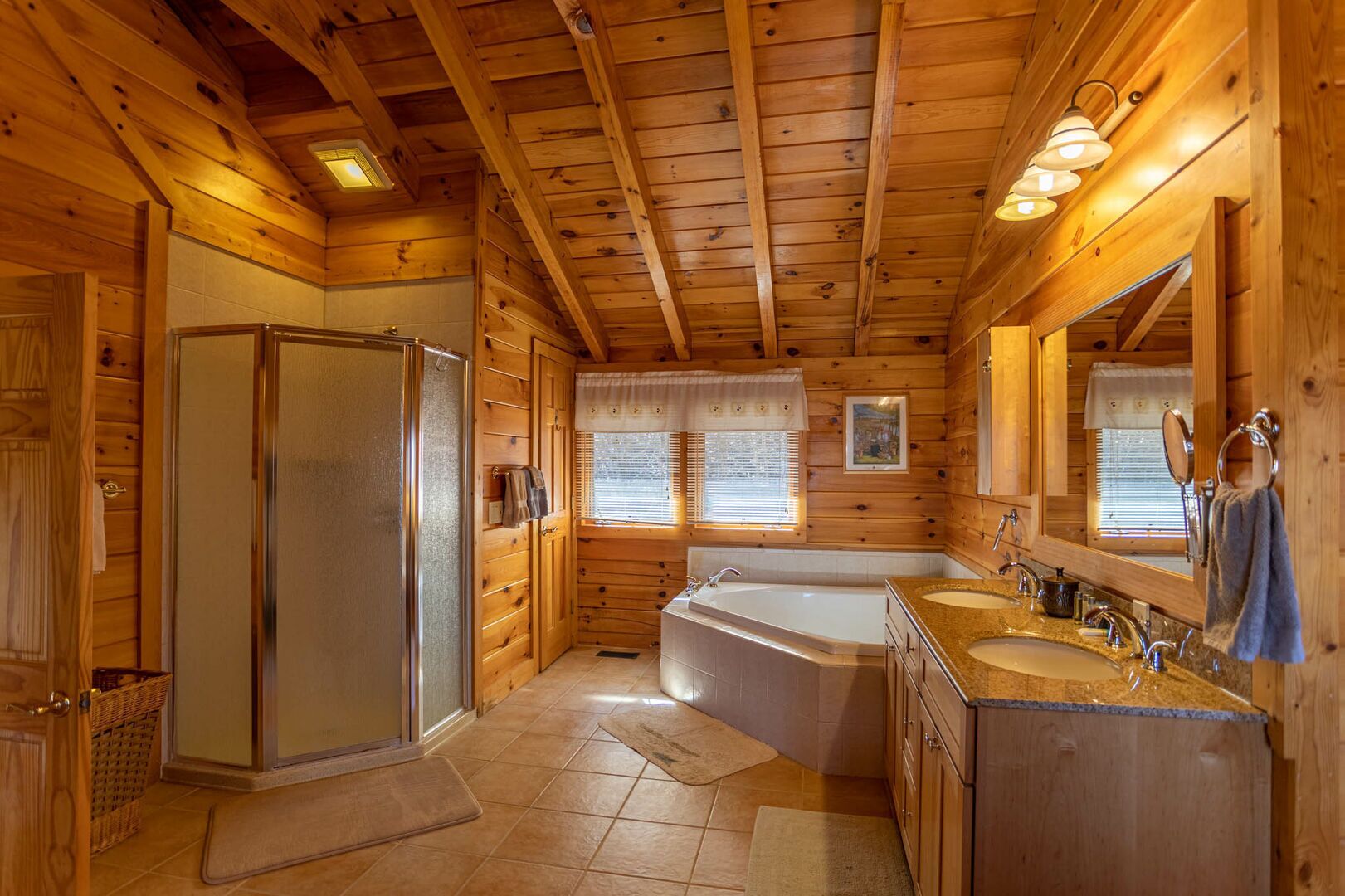 A wooden cabin bathroom with a shower, bathtub, and a vanity with a sink and mirror.