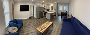 A modern kitchen with a central island, a dining area with a table and chairs, and a living room with a sofa and a coffee table. - 901 Bee’s Midtown Duplex in the heart of Overton Square 2280 (Memphis)