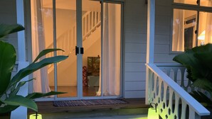 A wooden staircase leading to a porch with a railing, a sliding glass door, and a bench. - Villa Iris by Tahiti Homes  (Moorea-Maiao)