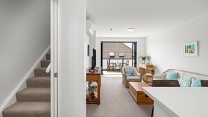 Un intérieur moderne comprenant un escalier, un coin repas et un salon avec un canapé et des fauteuils.