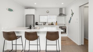 Une cuisine moderne avec un îlot central, des appareils en acier inoxydable et une horloge au mur.