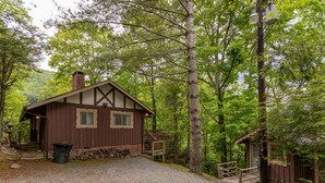 Une cabane rustique avec une allée en gravier, des marches en bois et un petit porche.