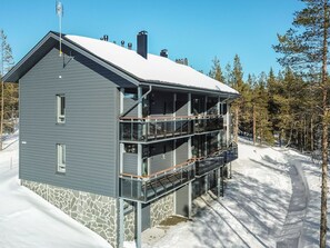 A modern multi-story building with a stone facade and a balcony on the ground floor. - Ylälänsi 3 as 11 by Interhome (Ylläsjärvi)
