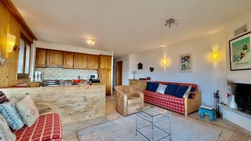 Een ruime woonkamer met een bank, een salontafel en een open haard.