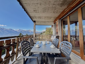 Una terraza con una mesa para dos, con vista a un paisaje montañoso.