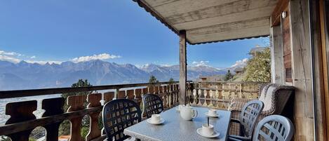 Eine Terrasse mit Tisch und Stühlen mit Blick auf ein Gebirge.