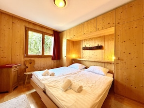 Una habitación de madera con una cama, un escritorio y una ventana.