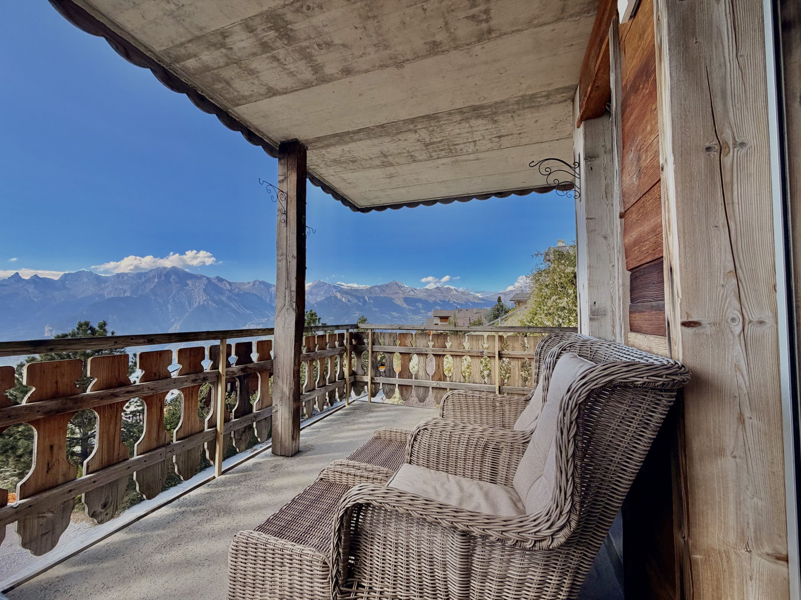 A balcony with wicker furniture and a view of mountains.