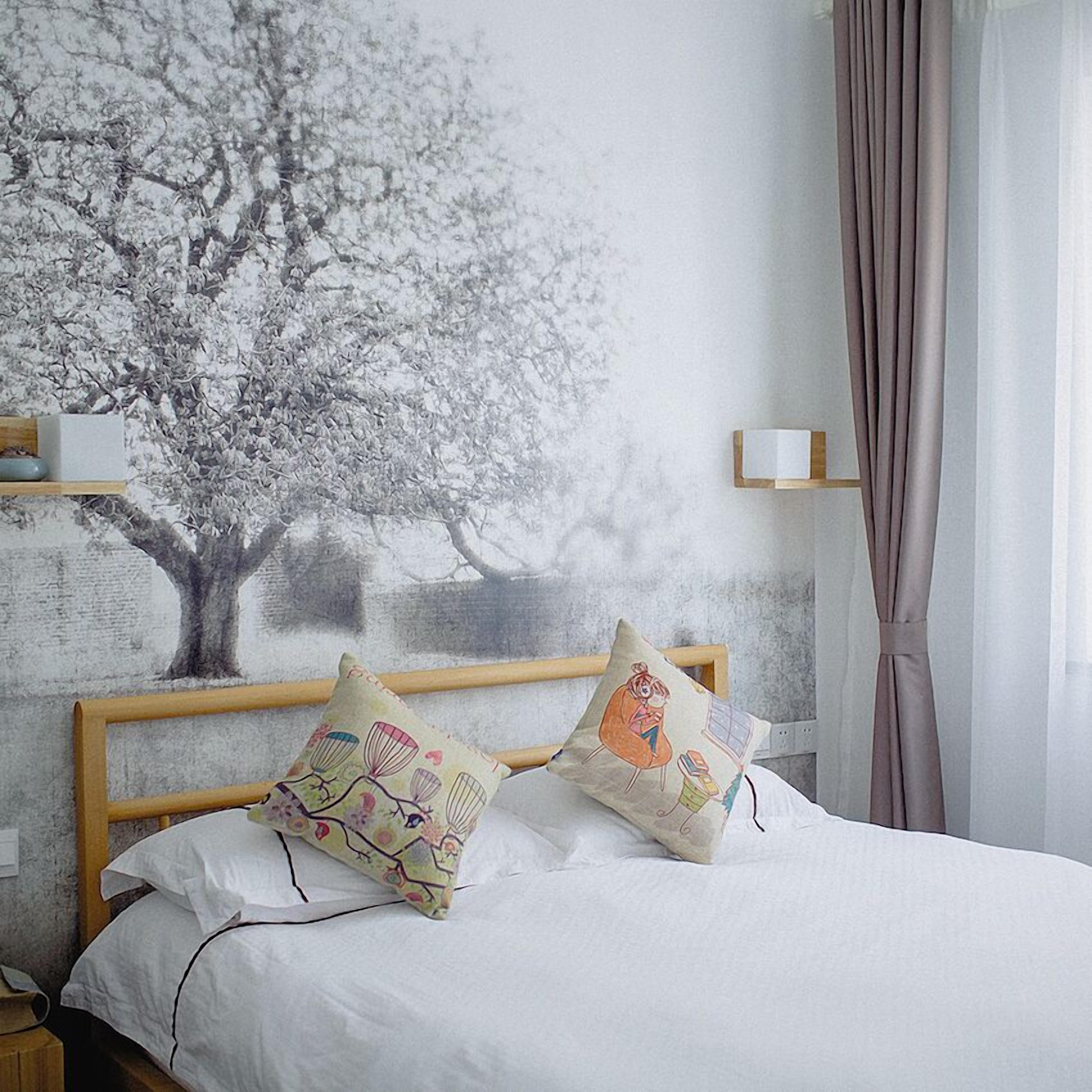 Een slaapkamer met een bed, twee kussens, een nachtkastje, een wandplank en een raam met gordijnen.