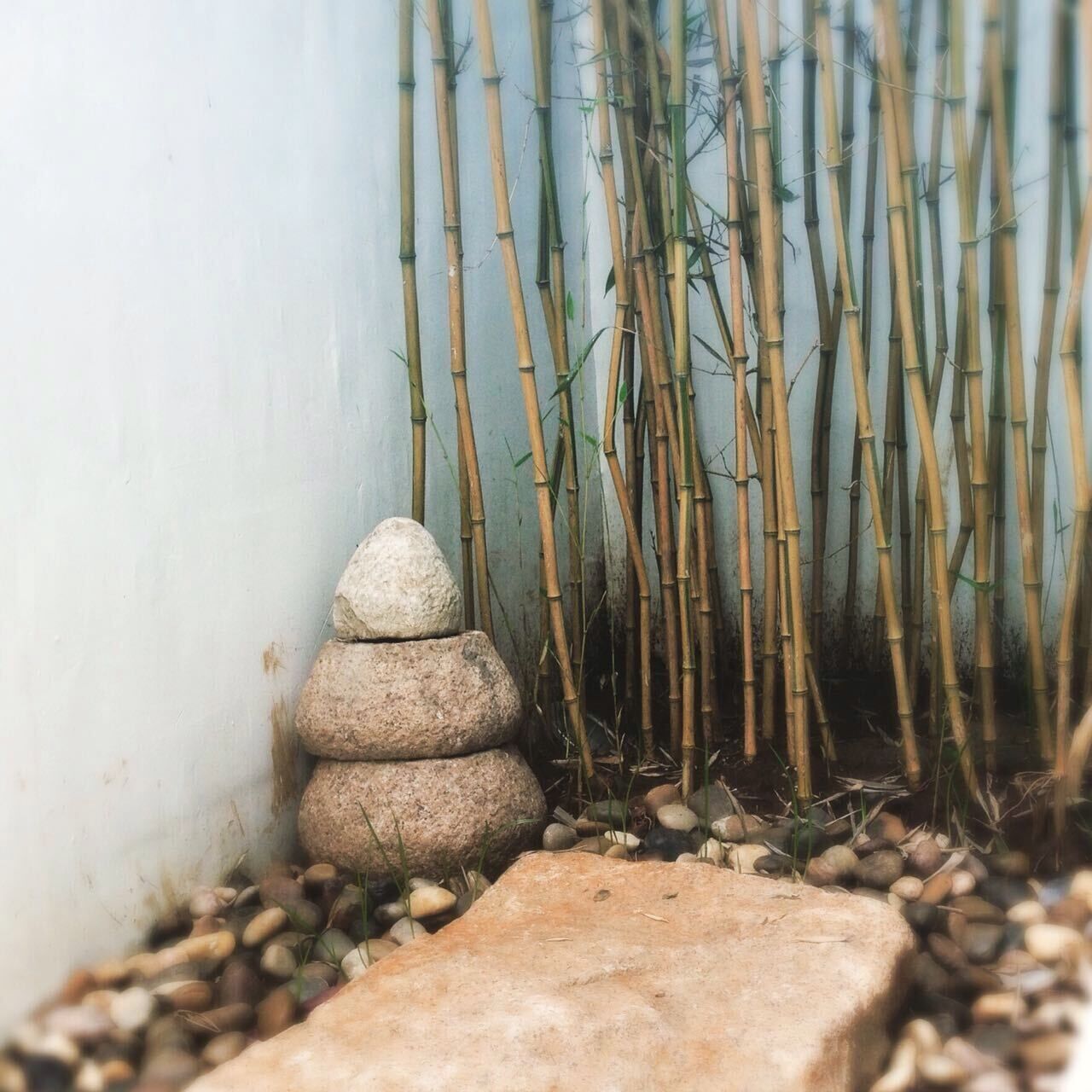 A stack of stones and bamboo against a wall.