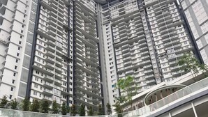 A high-rise residential building with multiple balconies and a curved pedestrian bridge.
