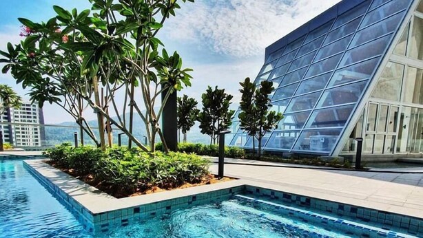 A swimming pool with clear blue water, surrounded by greenery and modern architecture.