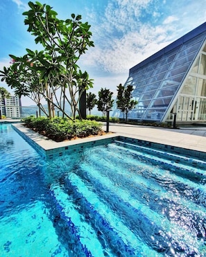 A swimming pool with clear blue water, surrounded by greenery and modern architecture. - Windmill By Annette Soon (Genting Highlands)