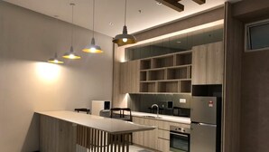A modern kitchen with wooden cabinetry, a central island, pendant lighting, and built-in appliances.
