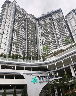 A high-rise residential building with multiple balconies and a curved pedestrian bridge.