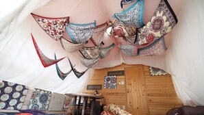 A tent-like room with hanging fabric decorations, a wooden table, and patterned rugs. - WOOD DESIGN PARK - Campground (Okazaki)