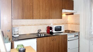 A compact kitchen with wooden cabinets, a microwave, a coffee maker, and a stove. - Magrappé M 544 - SKI LIFT studio 4 pers (Veysonnaz)
