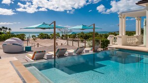 A pool area with lounge chairs and umbrellas, a gazebo, and a view of the ocean. - Exclusive Oceanfront Villa On Taylor Bay Beach! (Providenciales)