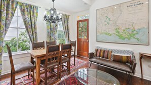 Un coin repas avec une table et des chaises en bois, un lustre et une grande carte de la Louisiane accrochée au mur.