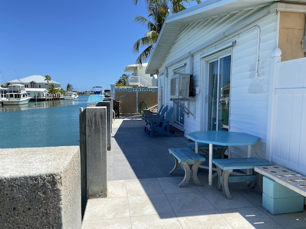 A waterfront property with a patio area featuring outdoor seating and a view of the marina. - 50’ dock on Vaca Cut, deep wide unlimited dockage. (Marathon)