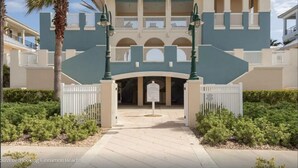 A two-story building with a white fence, a covered entrance, and a sign. - CB334 Romantic & Family Ocean & Golf Views - & bring your pet too! (Palm Coast)