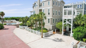 A beachfront property with a large house, a white picket fence, and a pool. - Beach Lawn Cottage: Premier Oceanfront Escape | Amazing Views | Steps to Beach | Beachfront Pools (Saint Simons Island)