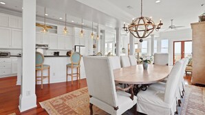 A spacious kitchen with white cabinetry, wooden chairs, and a large dining table. - Beach Lawn Cottage: Premier Oceanfront Escape | Amazing Views | Steps to Beach | Beachfront Pools (Saint Simons Island)