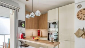 A modern kitchen with a wooden countertop, stainless steel appliances, and pendant lighting. - Le Newport by Interhome (Fréjus)
