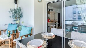 A dining area with a glass partition, wooden chairs, and a table set for two. - Le Newport by Interhome (Fréjus)
