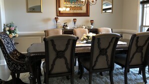 Comedor con una mesa redonda, seis sillas, una araña y cuadros en las paredes.