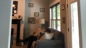 Un salón con un reloj original, un sofá y una chimenea.