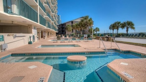 Un área de piscina hotelera con varias piscinas y sillones de descanso.
