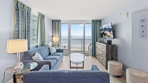 A modern living room with a sofa, a glass coffee table, and a television. - Avista Resort 720 - 3 Bedroom Oceanfront Condo with Lots of Amenities! (NORTH MYRTLE BEACH)
