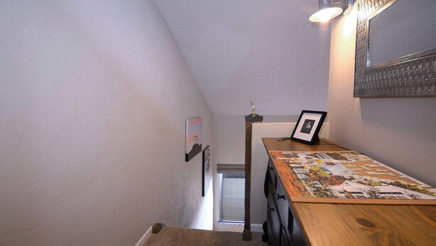 A narrow hallway with a wooden table, a framed picture, and a door leading to another room. - Snowcrest, Hot tub!  Walk to lifts! (Mt. Crested Butte)