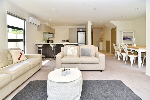A modern living room with a sofa, a round coffee table, and a dining area with chairs and a table.