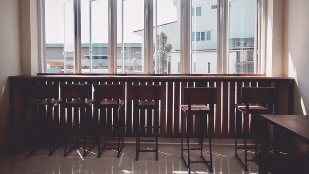 A room with a large window, wooden chairs, and a table. - More than Sleep Hostel Pak Chong - Khao Yai (Pak Chong)