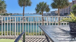 A balcony with a view of a marina, palm trees, and a building in the background.