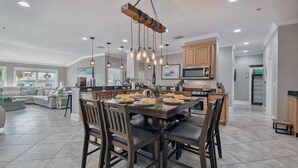 A spacious living area with a large dining table set for six, a kitchen with modern appliances, and a cozy seating area with a sofa and a coffee table.
