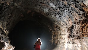 A person standing in a cave with a natural archway.